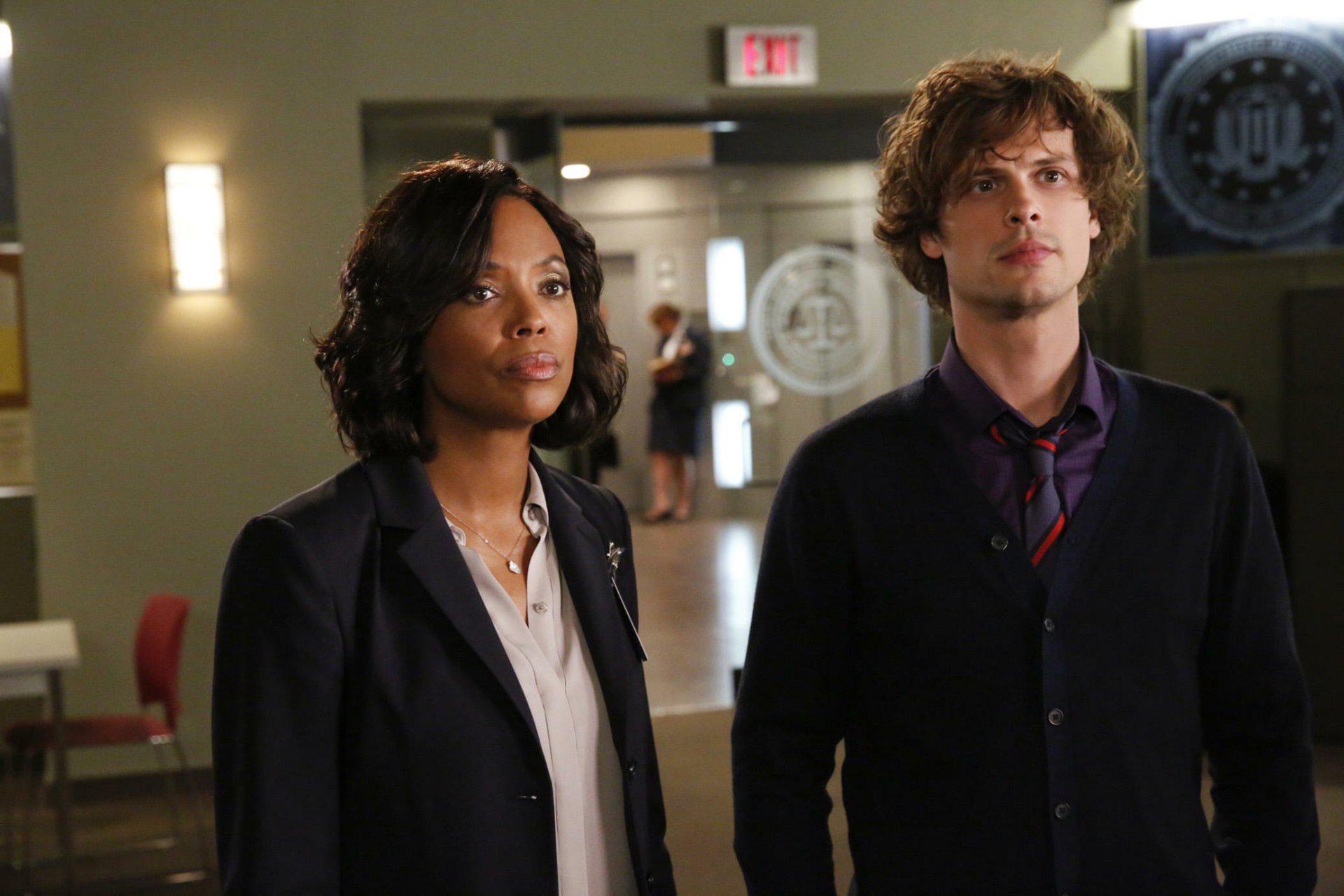 HD desktop wallpaper featuring two characters from Criminal Minds standing in an office environment.