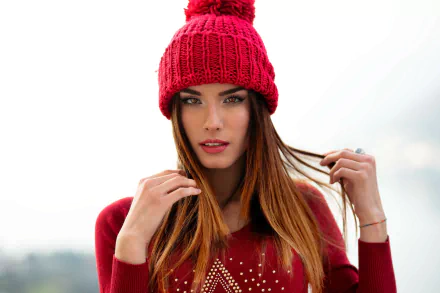 HD desktop wallpaper of a redhead model with brown eyes and lipstick, wearing a red knit hat and matching sweater, posing against a soft, out-of-focus background.