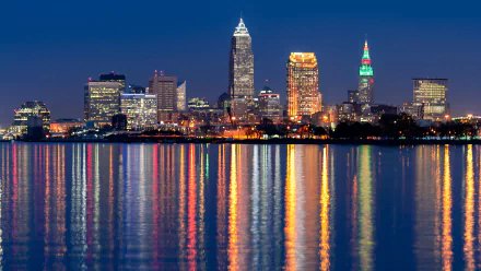 A vibrant 4K Ultra HD cityscape of Cleveland at night, showcasing illuminated skyscrapers reflecting on calm water.