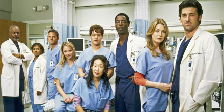 HD wallpaper featuring the cast of Grey's Anatomy in medical scrubs, posing in a hospital setting.