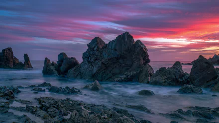 4K Ultra HD desktop wallpaper capturing a vibrant sunset over rocky ocean shores, blending dramatic sky hues with serene nature elements.