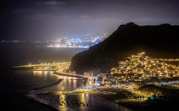 Nighttime view of a brightly lit man-made coastal town in Tenerife, with illuminated buildings and streets creating a vibrant HD desktop wallpaper background.