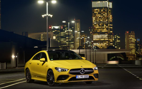 Yellow Mercedes-Benz CLA-Class car parked on a rooftop at night against a glowing city skyline — 8K Ultra HD PC desktop wallpaper