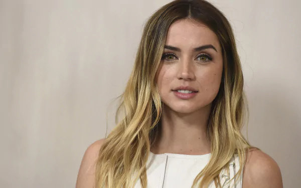 Portrait of Cuban actress Ana de Armas with long blonde hair and green eyes, featured in a high-definition desktop wallpaper.
