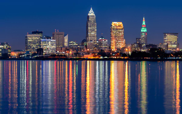 A vibrant 4K Ultra HD cityscape of Cleveland at night, showcasing illuminated skyscrapers reflecting on calm water.