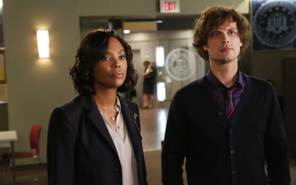 HD desktop wallpaper featuring two characters from Criminal Minds standing in an office environment.