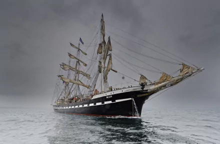 HD PC desktop wallpaper of a majestic barque sailboat vehicle with full masts gliding on calm gray seas beneath an overcast sky.