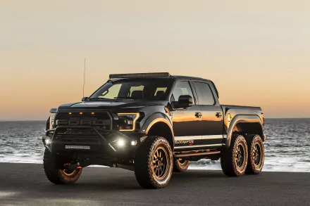 Black Hennessey VelociRaptor 6X6 Ford Raptor truck parked by the ocean at sunset, showcasing its rugged tuning and six-wheel design in a HD desktop wallpaper.