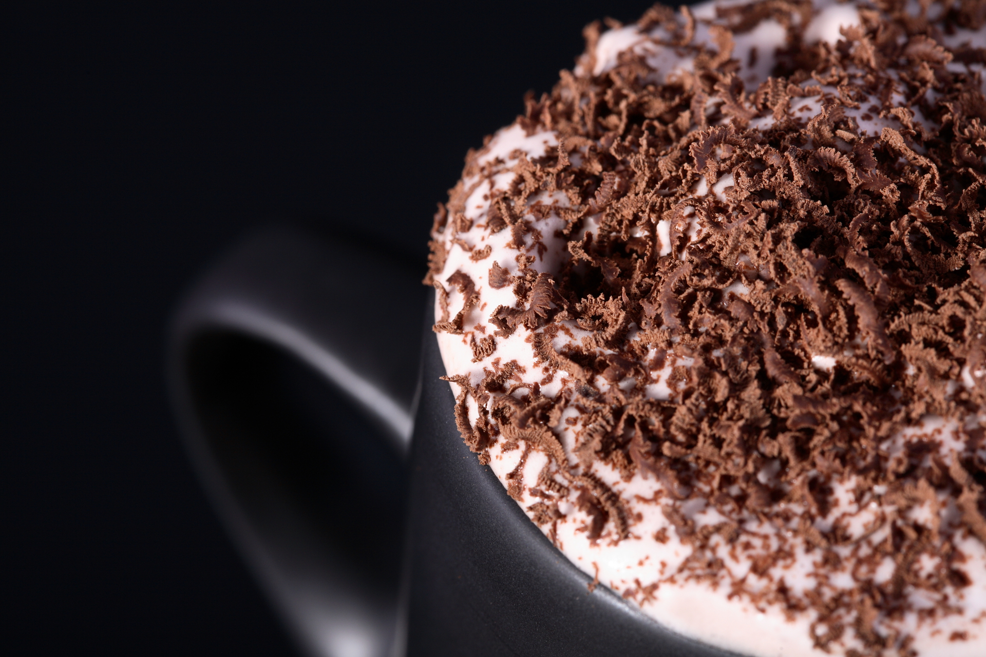 A close-up view of a beautiful cappuccino with foamy milk and dark brew in a white ceramic mug.