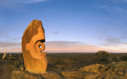 HD desktop wallpaper of a man-made statue in the Australian outback under a blue sky with scattered clouds.