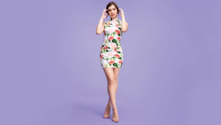HD wallpaper featuring American singer and actress Hailee Steinfeld, dressed in a floral print dress, standing against a light purple background.