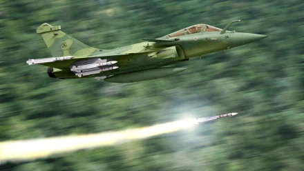 A Dassault Rafale fighter jet launches a missile, showcasing its advanced military capabilities. This HD wallpaper highlights the aircraft's sleek design against a blurred green background.