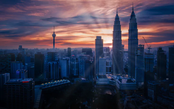 Sunrise over Kuala Lumpur cityscape, showcasing the iconic Petronas Towers and surrounding skyscrapers in Malaysia against a colorful sky.