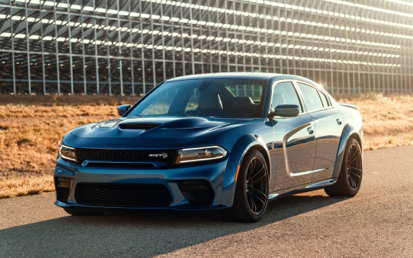 A blue Dodge Charger SRT Hellcat muscle car parked on a road with a grid-like structure in the background, captured in HD for a desktop wallpaper.