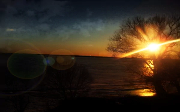 A serene sunrise over water, featuring silhouetted trees and vibrant colors, enhanced through Photoshop, makes for a stunning HD desktop wallpaper celebrating nature’s beauty.