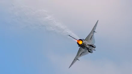 Saab 35 Draken military jet fighter warplane banking with afterburner aglow against a pale blue sky — HD PC desktop wallpaper and background.