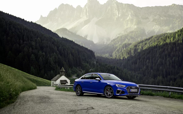 Blue Audi S4 compact car parked on a mountain road amid forested valleys and jagged peaks — 4K Ultra HD PC desktop wallpaper background.