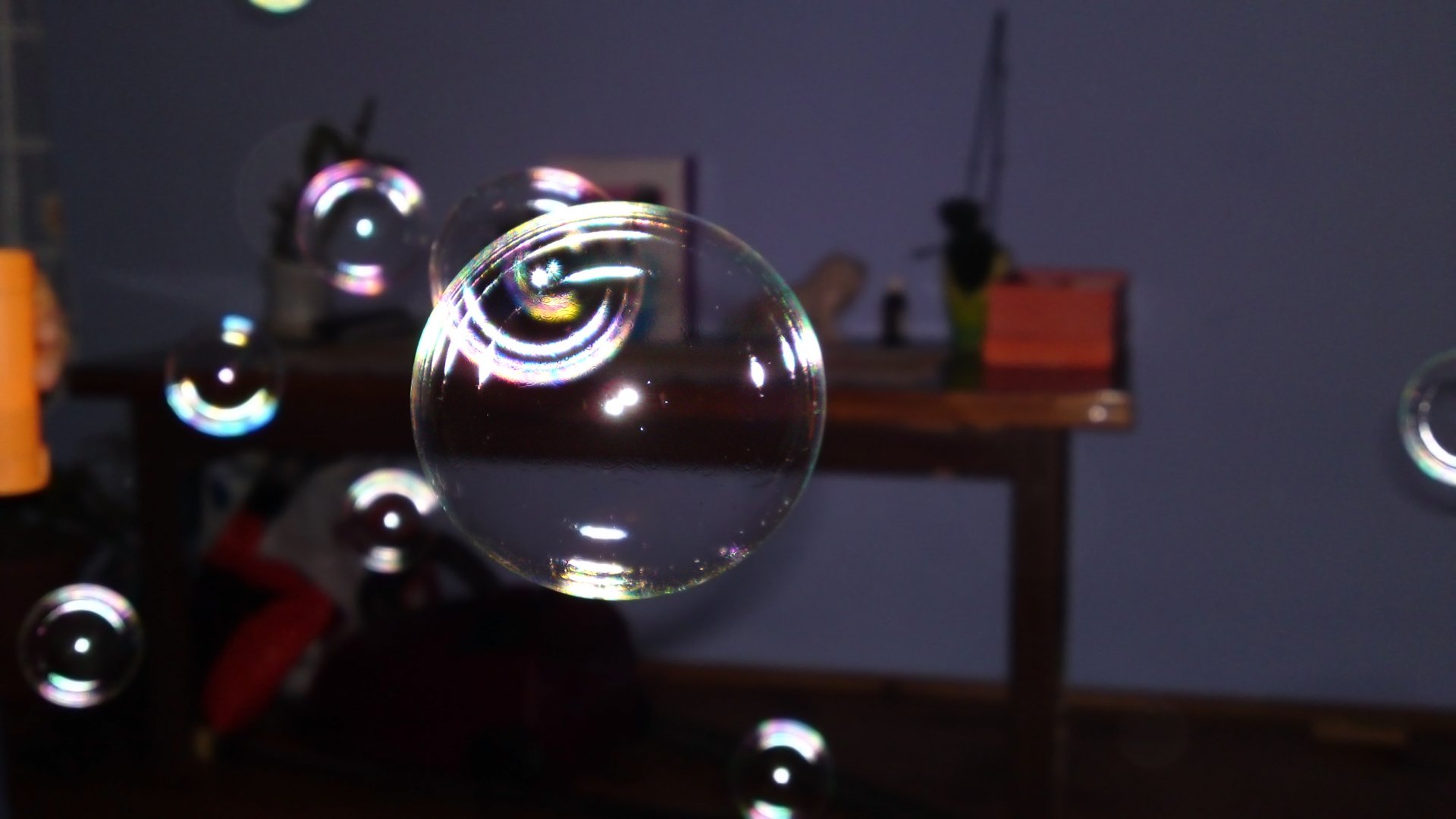 A close-up photograph of a floating bubble with colorful reflections, set against a blurred indoor background, presented as a 4K Ultra HD PC desktop wallpaper.