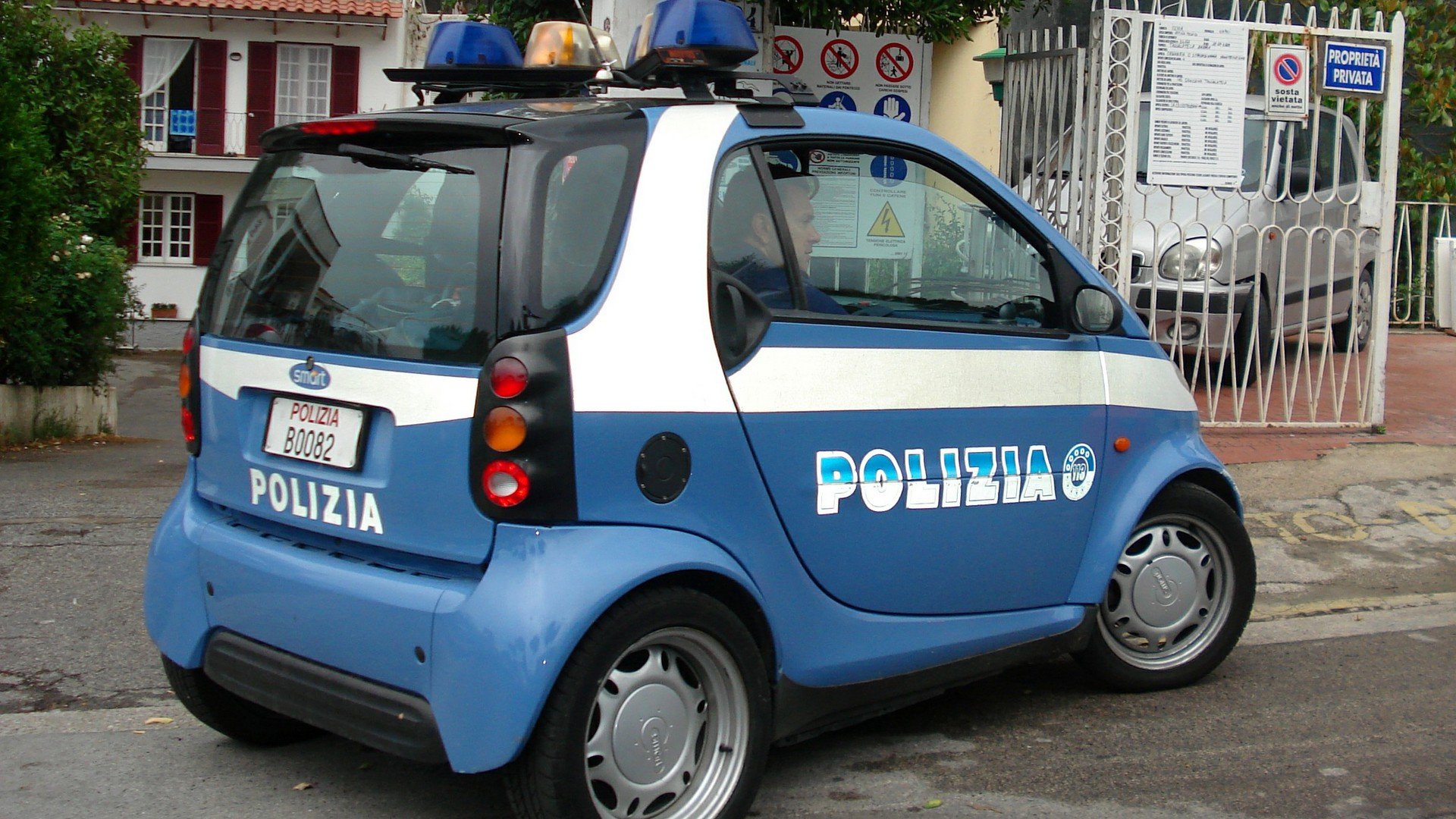 A compact blue and white police vehicle, adorned with lights on top, parked on a street. This HD wallpaper showcases the unique design of a smart police car.