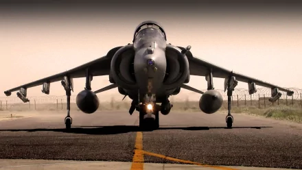 HD wallpaper of a McDonnell Douglas AV-8B Harrier II jet fighter shown head-on on a runway, exuding a powerful military presence.