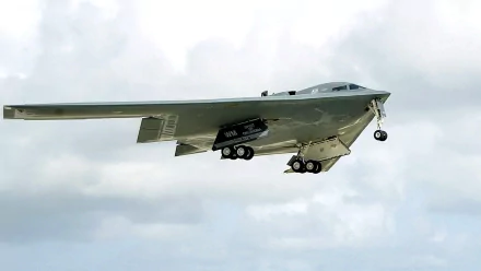 A Northrop Grumman B-2 Spirit stealth bomber in flight, showcasing its sleek design and advanced military technology against a cloudy sky. High-definition desktop wallpaper.