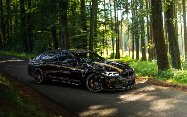 Black BMW M5 performance car parked on a sunlit forest road, glossy vehicle reflecting trees — 5K Ultra HD PC desktop wallpaper and background.