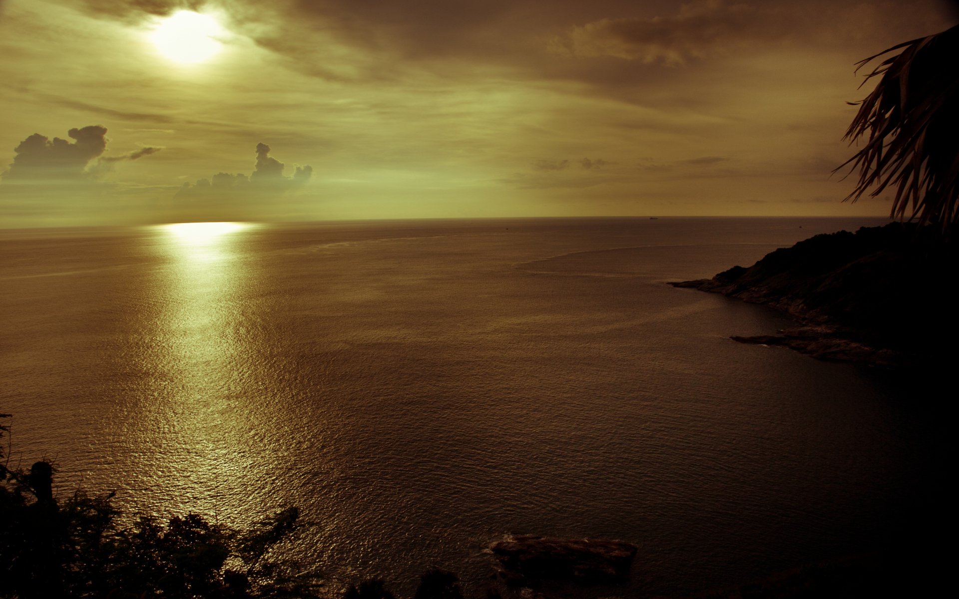 Golden sunset over the ocean in Phuket, Thailand, with vibrant clouds and their reflection on the water, captured in an HD desktop wallpaper.