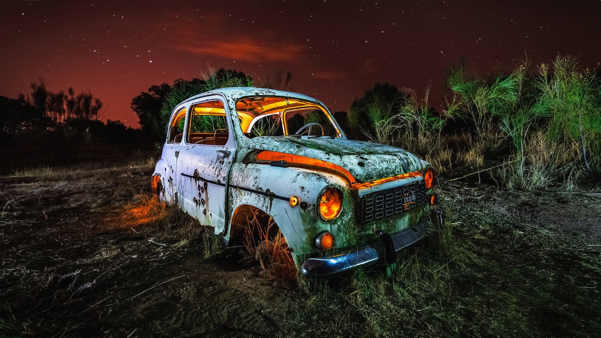A rusted, wrecked Seat car sits abandoned in a dark, eerie field under a starry night sky, captured in stunning 4K Ultra HD resolution.