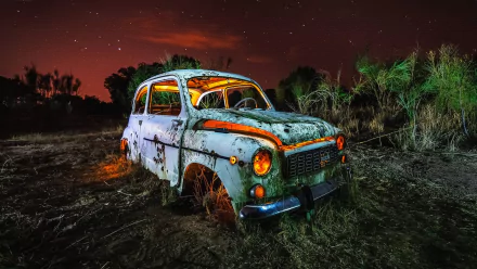 A rusted, wrecked Seat car sits abandoned in a dark, eerie field under a starry night sky, captured in stunning 4K Ultra HD resolution.