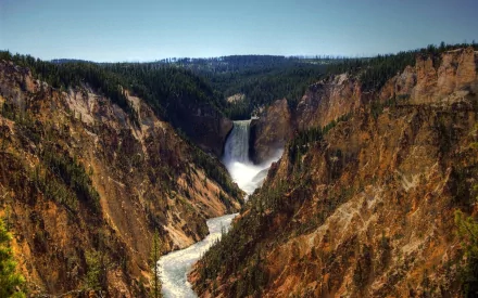HD PC desktop wallpaper: Yellowstone Falls cascading through a steep canyon, river winding below amid rugged cliffs and forested rim — dramatic nature scene.