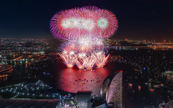 Nighttime cityscape of Yokohama, Japan, featuring vibrant fireworks over the water and illuminated buildings, captured in a stunning 4K Ultra HD photograph.