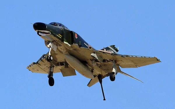 A McDonnell Douglas F-4 Phantom II in flight against a clear blue sky, showcasing its military design and features. High-definition desktop wallpaper and background image.