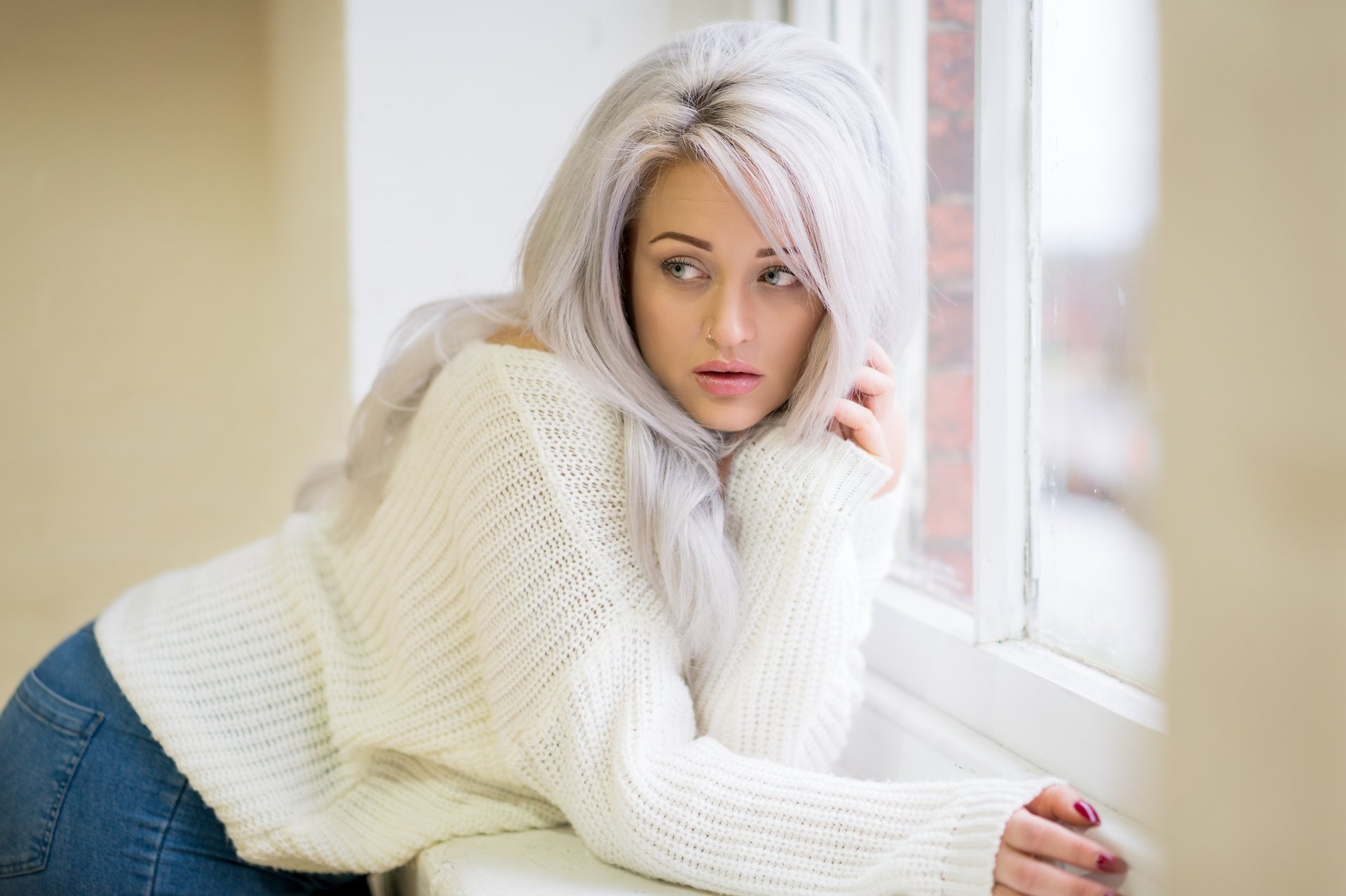 4K Ultra HD PC desktop wallpaper of a white‑haired woman model in a cozy white sweater, leaning on a sunlit windowsill with soft natural light and a neutral interior background.