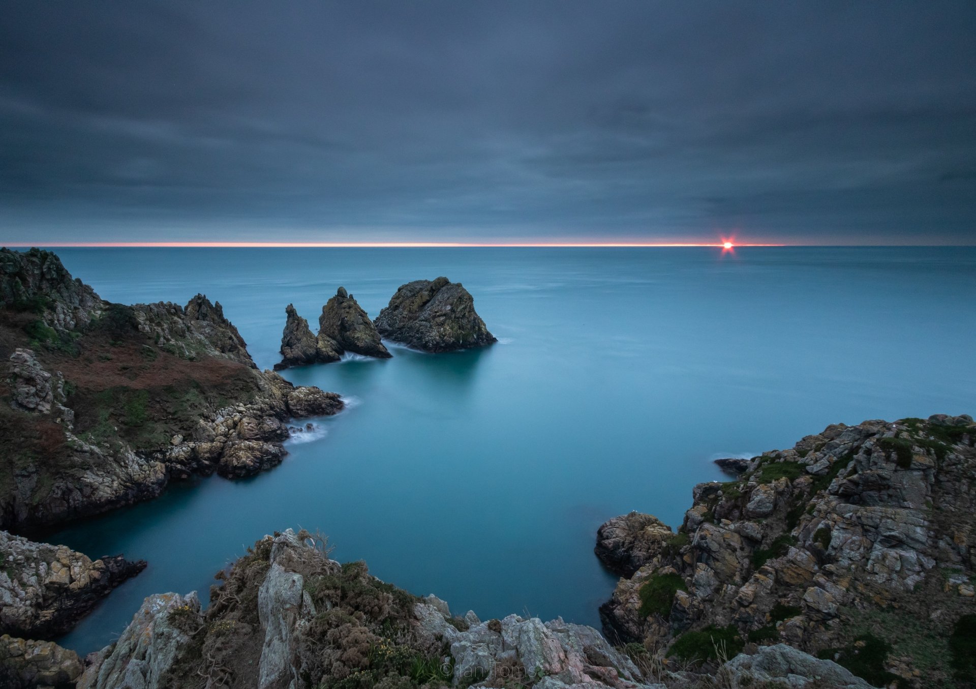 5K Ultra HD PC desktop wallpaper and background: ocean at sunset with a thin glowing horizon, sun glint and rugged rocky cliffs.
