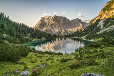 A serene mountain lake in the Austrian Alps reflects surrounding peaks and lush greenery, captured in stunning 4K Ultra HD landscape.
