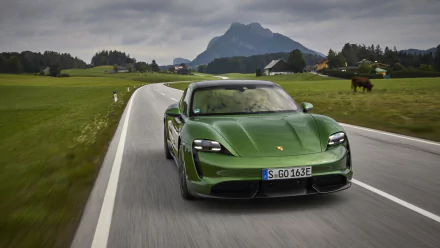 Green Porsche Taycan Turbo S electric vehicle on a winding rural road with mountains in the background — HD PC desktop wallpaper.