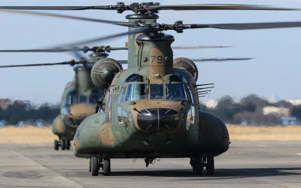 HD PC desktop wallpaper of military transport aircraft: front view of two Boeing CH-47 Chinook helicopters taxiing on an airfield.