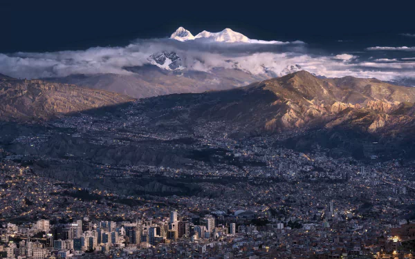 HD PC desktop wallpaper of La Paz, Bolivia: snow-capped Illimani mountain rising above a sprawling man-made cityscape.