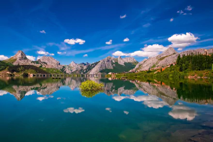 Riaño mountain landscape photography: HD desktop wallpaper showing a crystal-clear lake mirroring jagged peaks, blue sky and lush green shores.