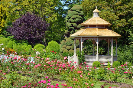 A vibrant park scene featuring blooming flowers surrounding a wooden gazebo, captured in HD quality for a serene desktop wallpaper background.