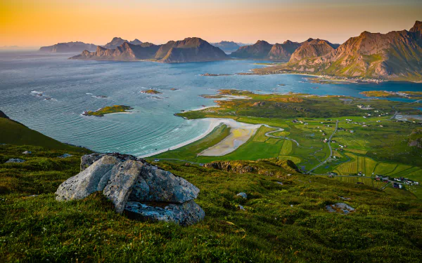 A breathtaking 4K Ultra HD photo of mountains and coastline in the Lofoten Islands, Norway, featuring vibrant green fields and calm waters during sunset.