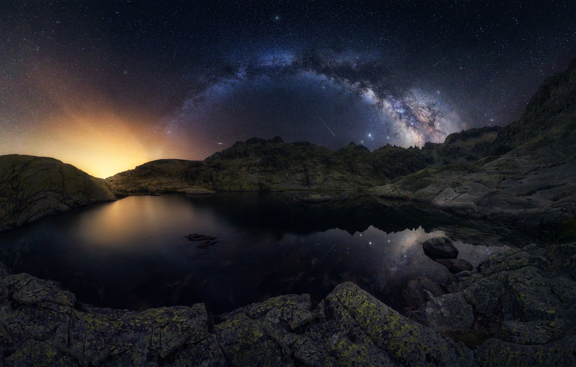 HD PC desktop wallpaper: night mountain lake reflecting the Milky Way and starry sky, serene nature scene with rocky foreground.