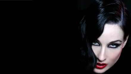 A striking HD desktop wallpaper featuring celebrity Dita Von Teese, emphasizing her dramatic look with dark hair, bold makeup, and vivid red lips against a black background.