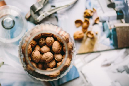 4K Ultra HD PC desktop wallpaper: close-up of walnuts in a glass jar on a sunlit kitchen surface, nut food walnut still life.