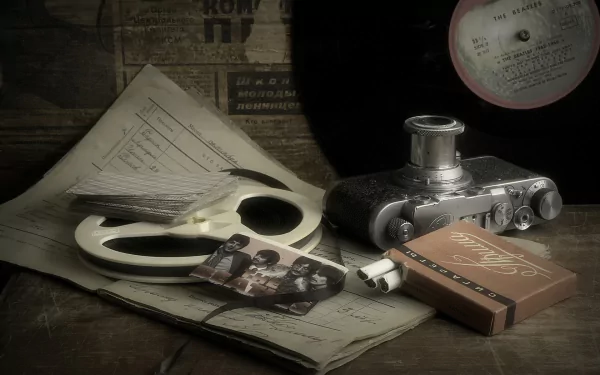 Vintage-themed HD desktop wallpaper featuring a retro camera, a cigarette pack, The Beatles vinyl record, and nostalgic photography elements on a rustic surface.