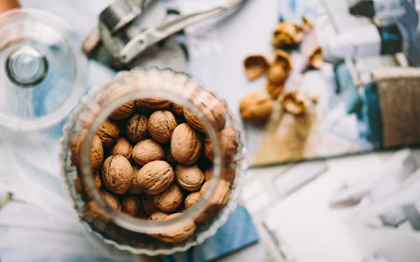 4K Ultra HD PC desktop wallpaper: close-up of walnuts in a glass jar on a sunlit kitchen surface, nut food walnut still life.