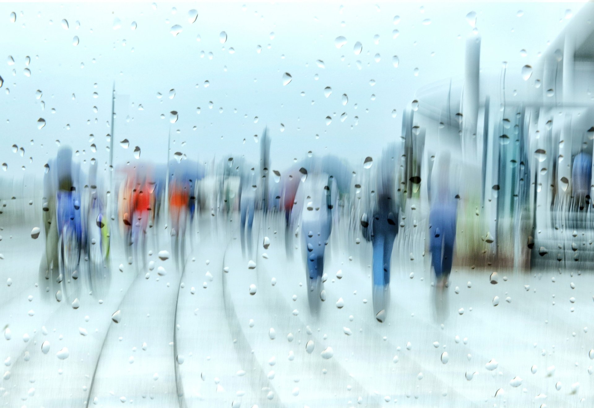 Artistic HD desktop wallpaper featuring blurred people walking in the rain, viewed through raindrop-covered glass.