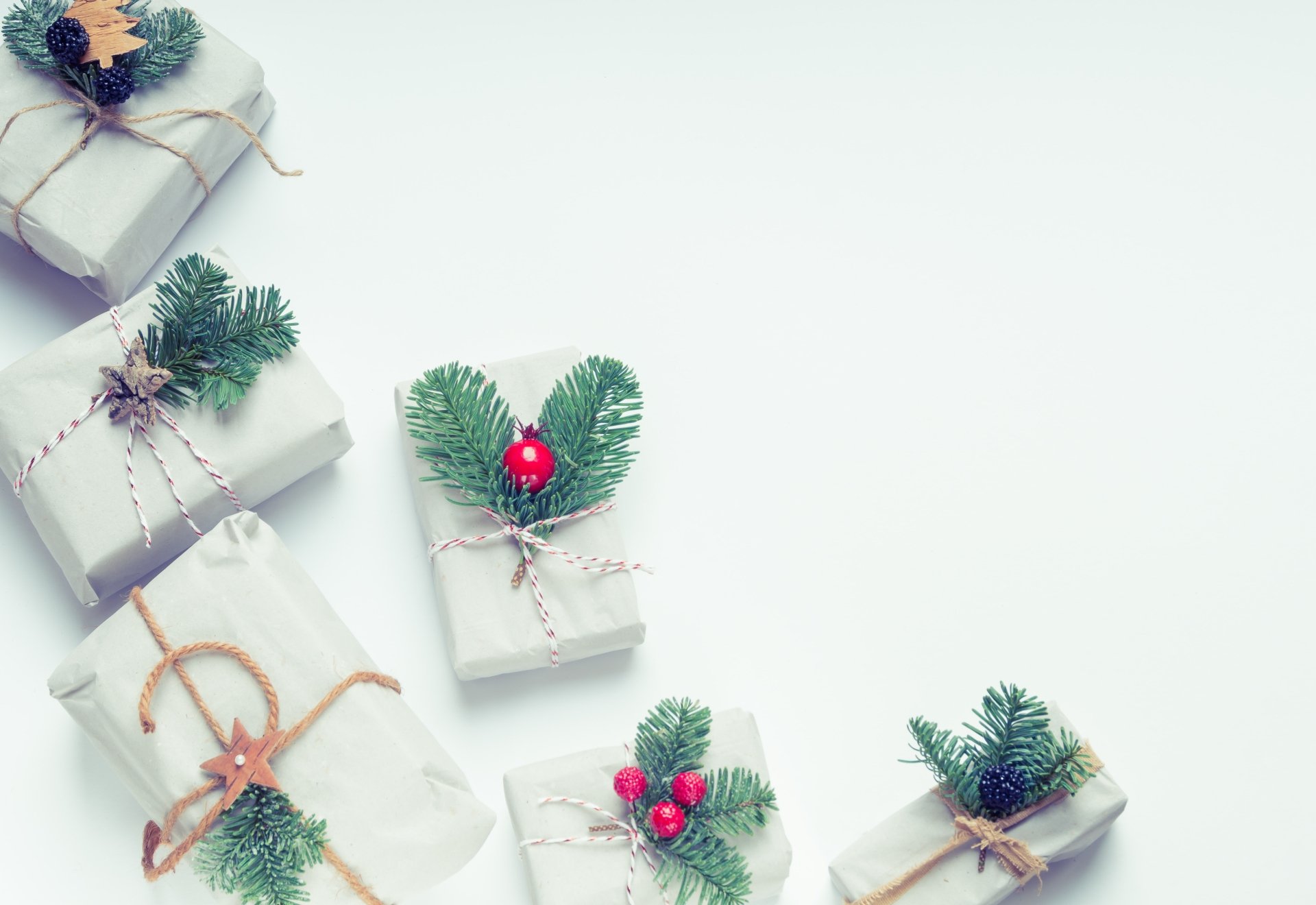 5K Ultra HD PC desktop wallpaper: minimalist Christmas scene of white gift boxes decorated with pine sprigs, red ornaments and twine on a pale background.