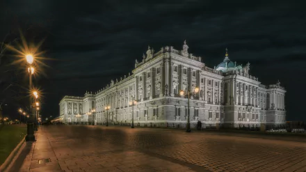 Night view of the Royal Palace of Madrid, Spain, showcasing the illuminated man-made palace against a dark sky in 8K Ultra HD quality.