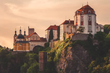 A stunning HD desktop wallpaper featuring man-made Czech Republic architecture with a historic castle perched on a rocky cliff at sunset.